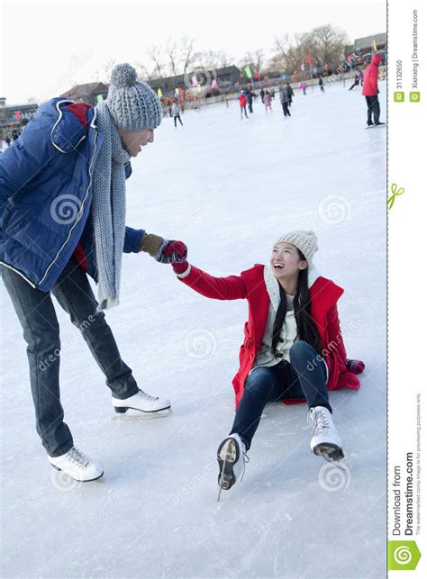 young woman falls   ice  skating boyfriend helps