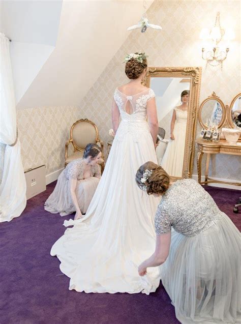 the bride gets ready in the boudoir wearing her beautiful wedding dress as her bridesmaids help