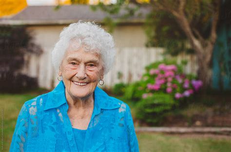 happy portrait of old elderly woman in backyard by stocksy