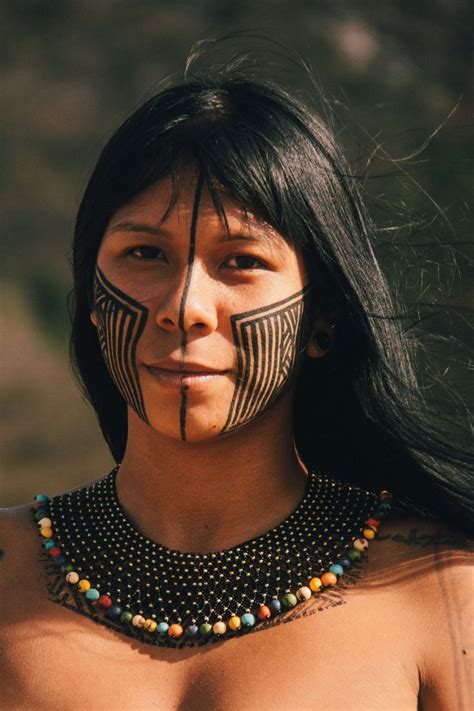A Native American Woman With Painted On Her Face And Chest Is Looking