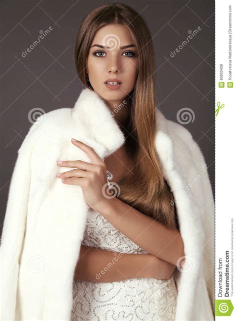 beautiful woman with long hair wears luxurious white fur coat stock
