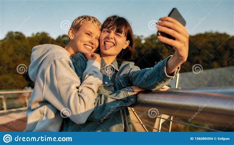 lesbian couple standing on the bridge and making faces while taking a