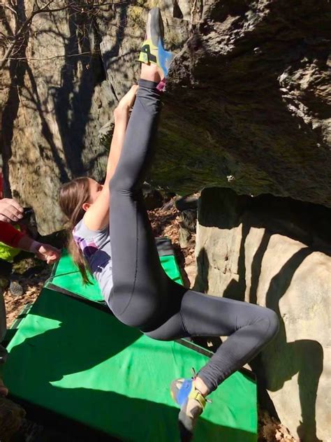A Woman Is Doing Yoga On A Mat In Front Of A Rock Wall And Holding Her