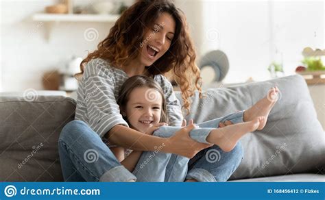 mother playing with daughter seated on couch having fun