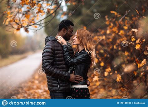 Interracial Couple Posing In Blurry Autumn Park Background Stock Image