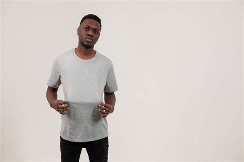 Black Man Holding T Shirt Standing Against White Background · Free