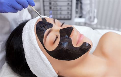 the procedure for applying a black mask to the face of a beautiful
