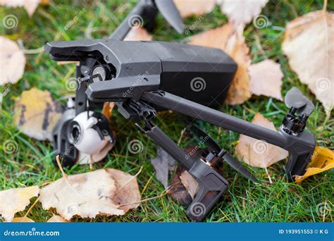 broken black quadcopter drone uav lying  green grass lawn  ground  crash accident