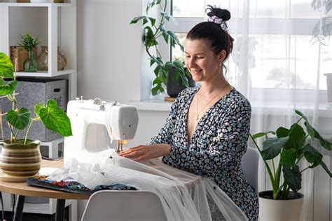 a woman sews tulle on an electric sewing machine in a white modern