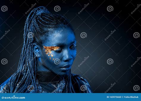 jonge afrikaanse vrouw met afro haarstijl en gouden glanzende   studio opname blauw