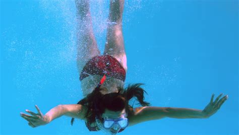 happy brunette underwater in swimming pool wearing snorkel