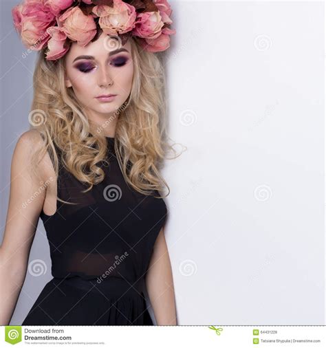 beautiful cute girl blonde in black fashion long dress and with a wreath on his head in the
