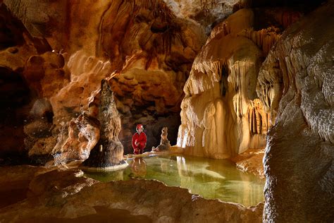 photo grotte de saint marcel ardeche speleo accroupie au bord dun gour avec eau verte