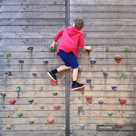 boy climbing  climbing wall toughness rear view stock photo