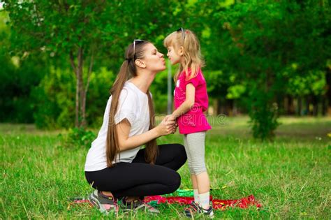 lovely little daughter kiss mother outdoor portrait of