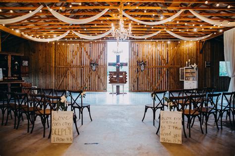 elegant romantic barn wedding ceremony decor with string market lights ceiling draping and