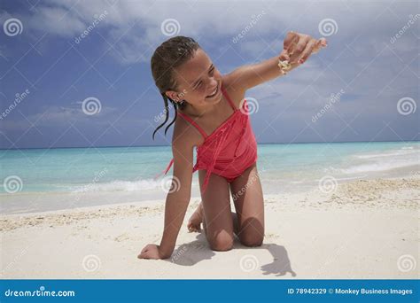 kneeling girl showing a crab sheï¿½s collected on the beach stock image