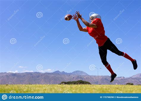 Mixed Race Male American Football Player Jumping In The