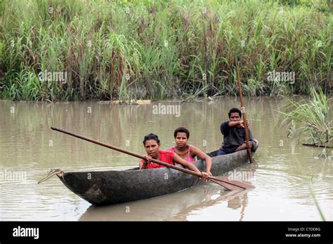 three girls in a dugout canoe on a river in papua new guinea stock