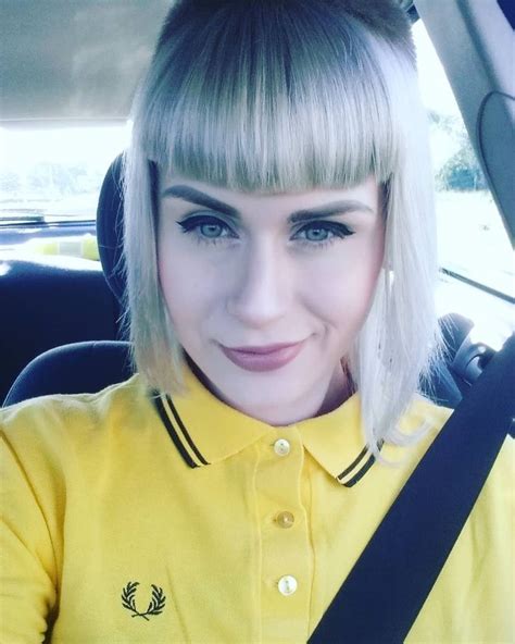 A Woman With Blonde Hair And Bangs Sitting In A Car
