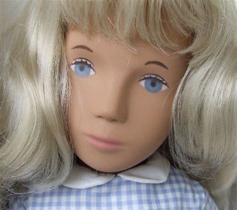 A Doll With Blonde Hair Wearing A Blue And White Shirt On Its Head