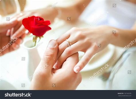Newly Married Couple Holding Hands With Rings Against