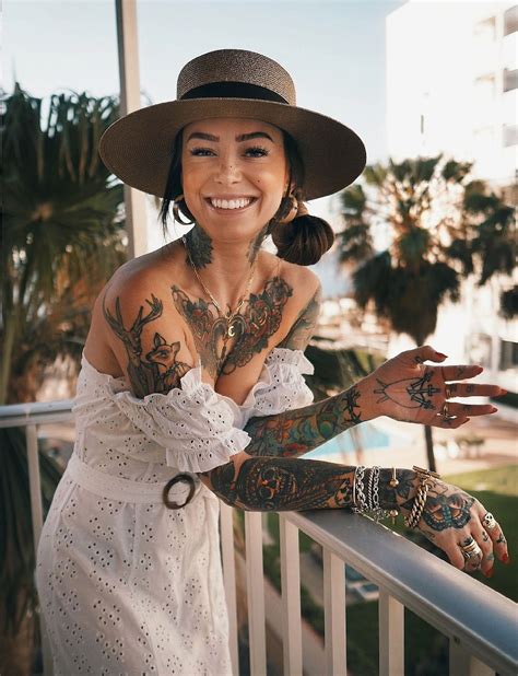 a woman with tattoos on her arm and arms leaning against a railing