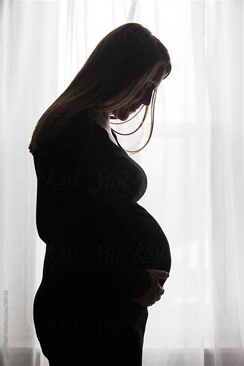 Silhouette Of A Pregnant Woman Standing In Front Of Window By Holly