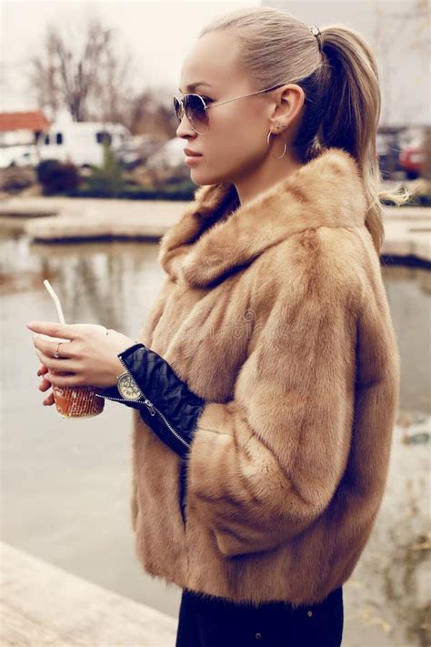 blond woman wearing luxurious fur coat and sunglasses stock image