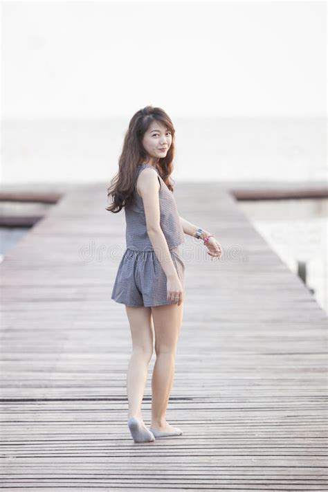 beautiful asian woman walking on wood pier with relaxing emotion and smiling to camera use for