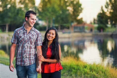 Mixed Race Couple Spending Quality Time Together Walking Around A Lake
