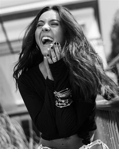 A Woman With Long Hair Is Laughing And Holding Her Hands To Her Mouth