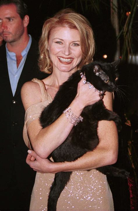 A Woman Holding A Black Cat In Her Arms And Smiling At The Camera While