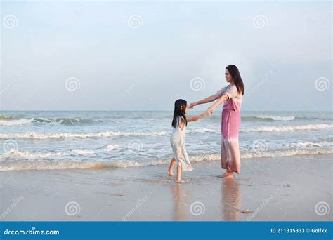 Asian Mom And Daughter Relax And Dancing Together On Sea Beach On