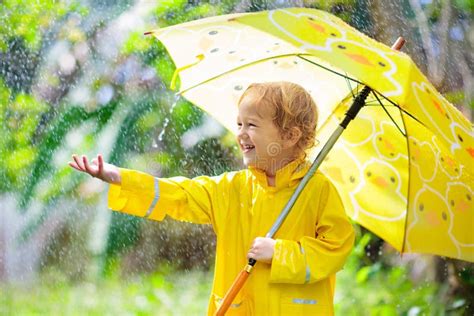 kind das im regen spielt kind mit regenschirm stockfoto bild von
