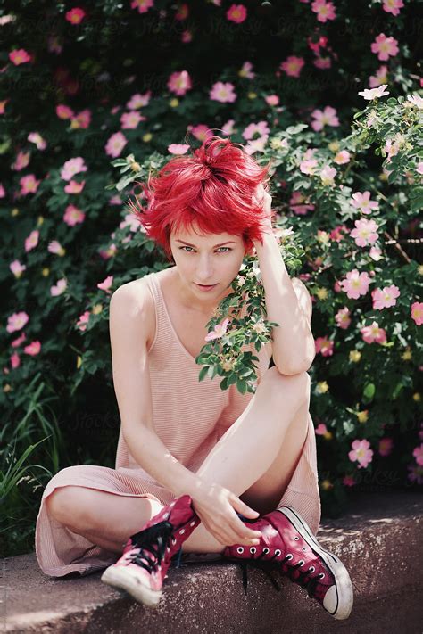 caucasian female  bright red hair sitting   flowering briar