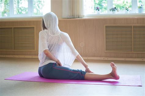 Ung Smal Kvinna I Vit Hodie Som Sitter På Yoga Mattan Och Som Utför En