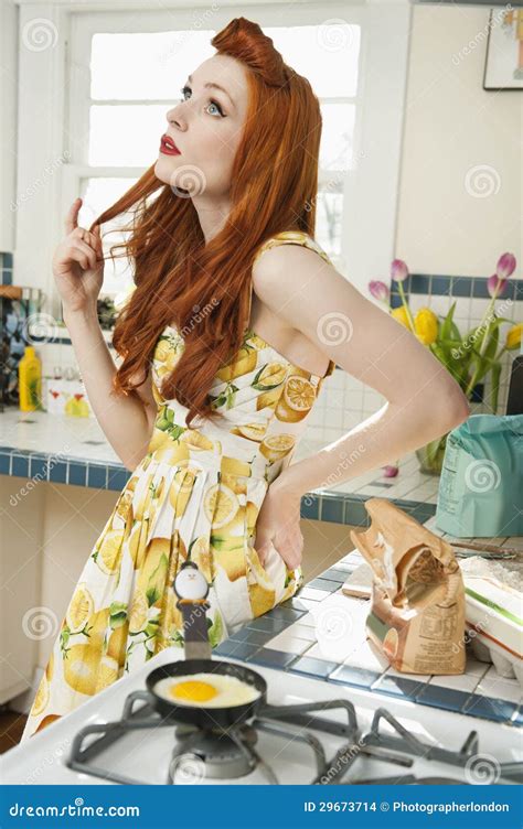 Young Woman At Kitchen Counter Thinking While Looking Up With Hand On