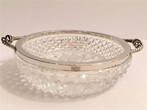 glass bowl sitting  top   white table    silver plate  handles
