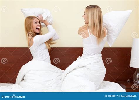 two girls having a pillow fight in bedroom stock image image of women