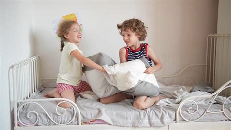 the brother and the sister have arranged fight by pillows on a bed in a bedroom stock footage