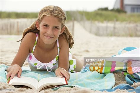girl lying on beach reading book smiling portrait bildbanksbilder