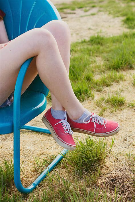 side image of teen with legs crossed over arm of chair by stocksy