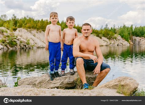 Father And His Two Sons Shirtless On The Shore Of The Pond