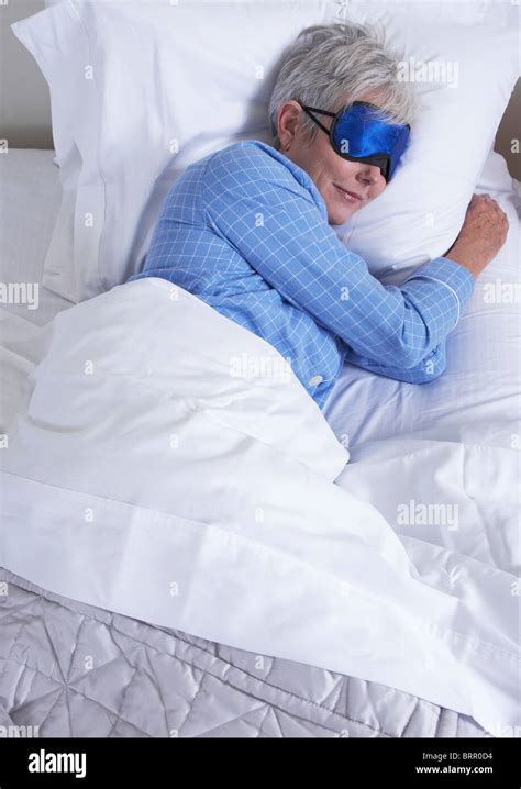 High Angle View Of Mature Woman Wearing Sleep Mask Lying In Bed Stock