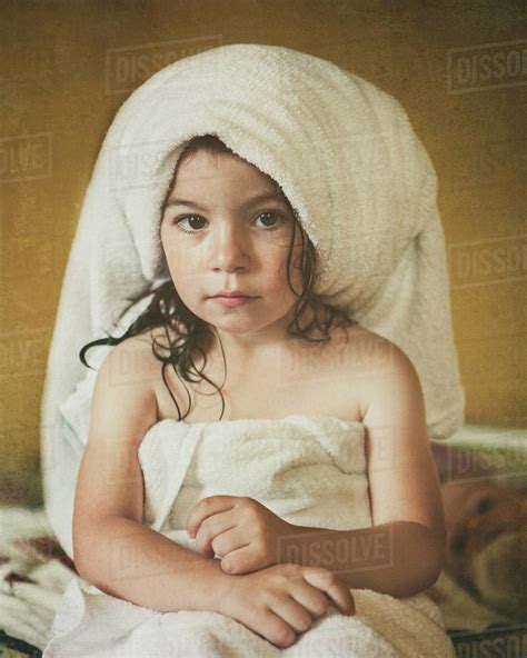 Portrait Of A Girl Sitting On Bed Wrapped In Towels After A Bath