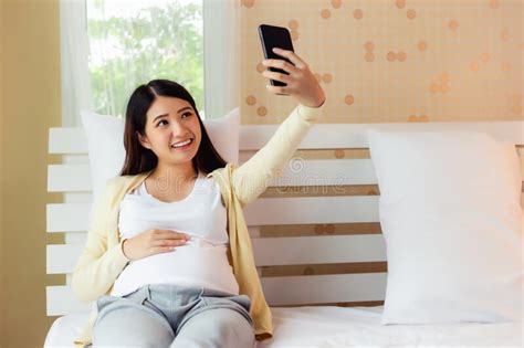 happy girl with smartphone taking selfie at home stock