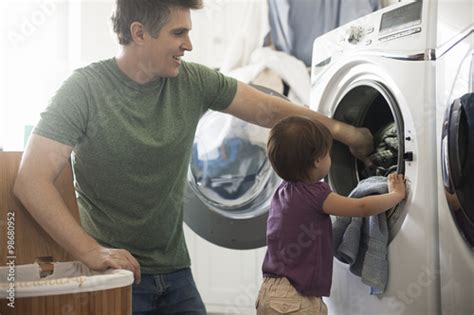 Father And Daughter Removing Laundry From Washing Machine Acheter