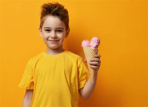 baby boy knul die aardbei ijs eet  wafels  blij dat hij lacht op gele achtergrond stock