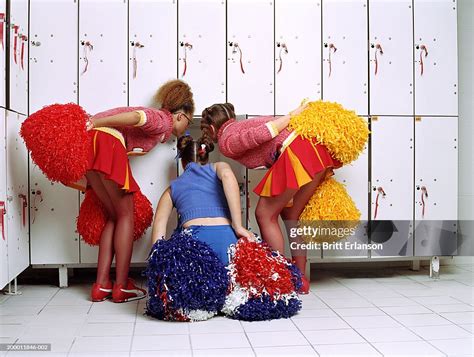 Three Cheerleaders In Locker Room Peering In Locker Rear View Photo
